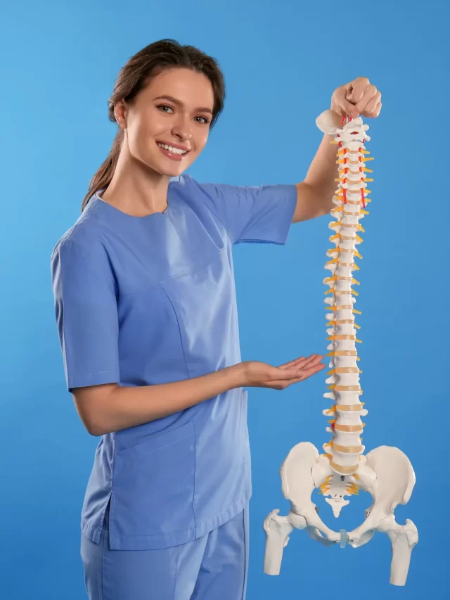 female-orthopedist-with-human-spine-model-against-blue-background